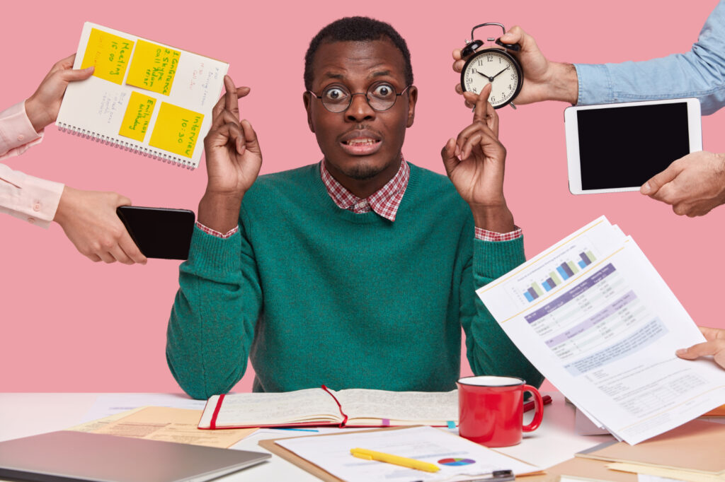 horizontal shot wishful dark skinned man crosses fingers makes wish dressed green sweater prepares examination session surrounded with alarm clock touchpad 1